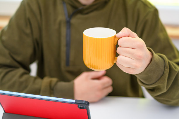 坐在桌旁的男子端着一杯茶图片下载