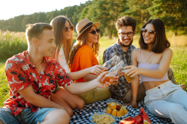 一群快乐的朋友在夏日公园里喝着啤酒欢呼。图片下载