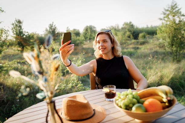 快乐的女人自由职业者与朋友通过视频通话，而放松舒适的豪华帐篷在阳光明媚的一天。豪华户外露营帐篷，适合夏季度假度假。生活方式的概念图片下载