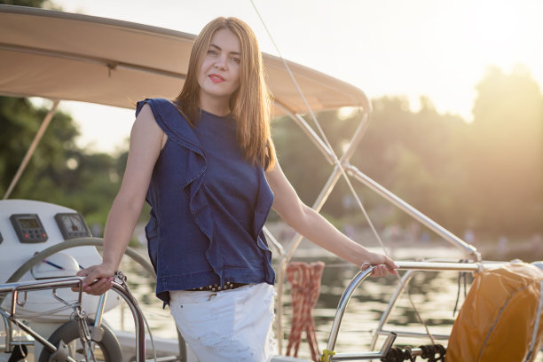 在一个阳光明媚的夏日，美丽的女人在河边放松在游艇的前端图片下载