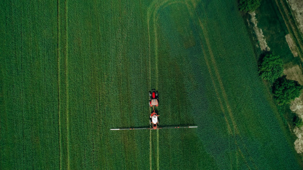 拖拉机春季用喷雾器对麦田喷洒农药的看法。图片下载