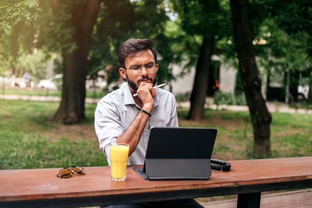 夏天在咖啡馆工作的沉思的亚洲商人。图片下载
