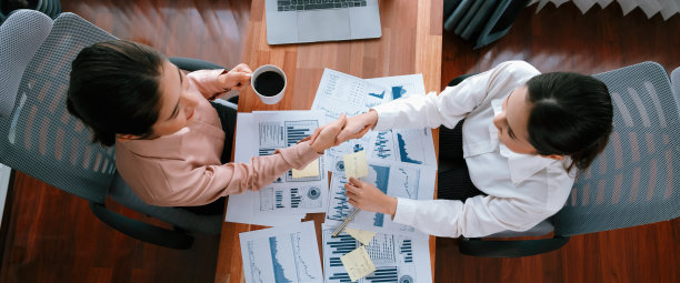 俯视图亚洲女商人在办公桌上握手。热情的图片下载