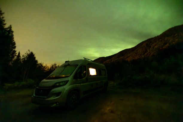一辆房车停在北极光下的山上图片下载