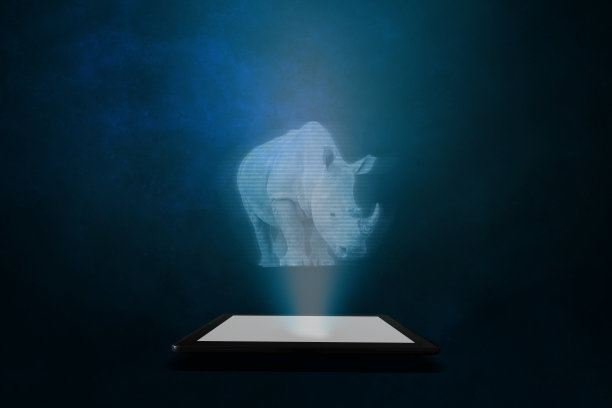 一个犀牛的全息图投射在一个抽象的蓝色背景的平板上。对动物的未来主义描绘。图片下载