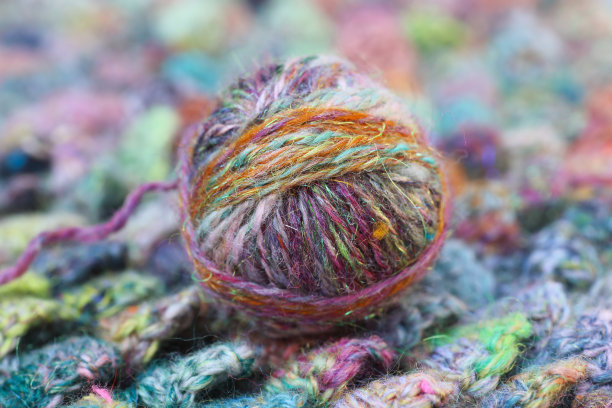 钩针奶奶方块在沉默的彩虹色与钩针钩的工艺作品特写。传统纺车上手工纺纱的漂亮球。图片下载