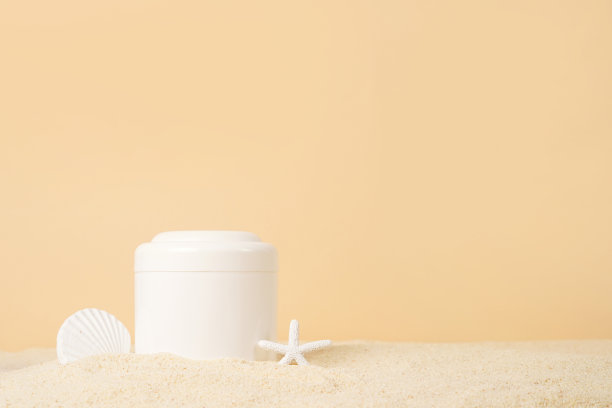 化妆霜在白色的瓶子与海星上的沙子在黄色的背景，复制空间。UVA和UVB防护。夏天的化妆品图片下载
