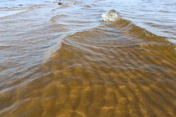 透明的波浪在海水与阳光眩光和涟漪在沙滩底部。图片下载