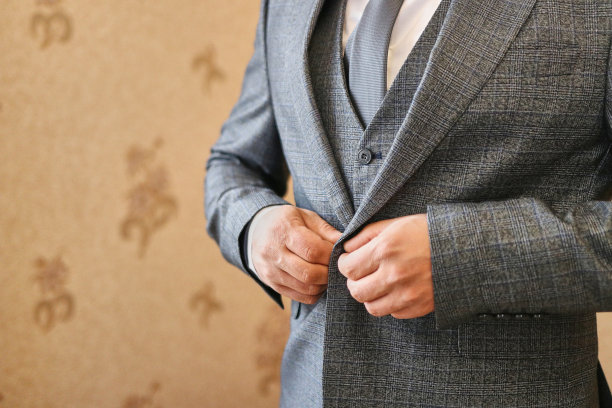 新郎一边穿衣服一边扣扣子。准备婚礼庆典。图片下载