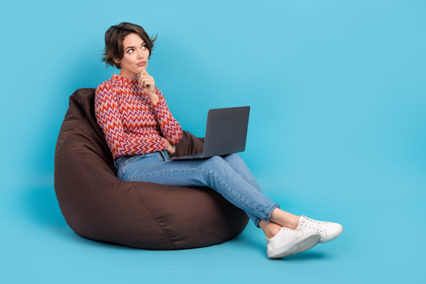 全身照片怀疑不确定的女人穿着粉红色的衬衫打字装置看起来空的空间孤立的蓝色背景图片下载