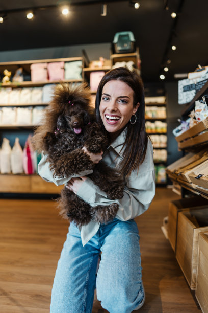 宠物店里有个带着贵宾犬的年轻女人图片下载