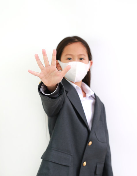 小女孩穿着学生服，戴着防护面罩，白色背景上有手停标志。注意他的手。图片下载