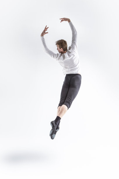活跃的专业高加索英俊的年轻运动员男子摆出飞行芭蕾舞姿势，举起双手，穿着白衬衫图片下载