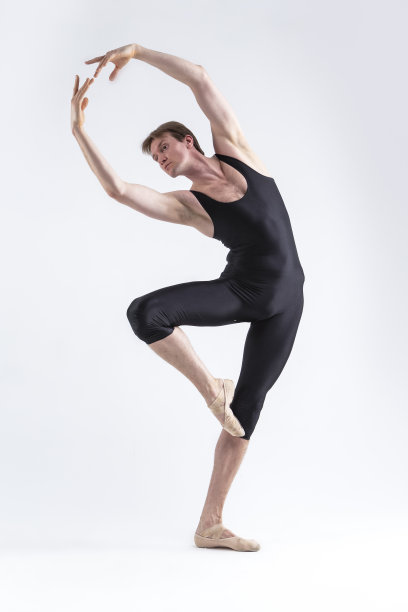 一名专业芭蕾舞男演员，身穿黑色紧身衣的年轻男子在舞蹈室内摆出平衡的舞蹈姿势。图片下载