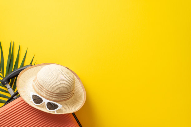 热带之旅概念。橙色行李箱的俯视图照片，草帽和太阳镜在孤立的亮黄色背景与复制空间图片下载