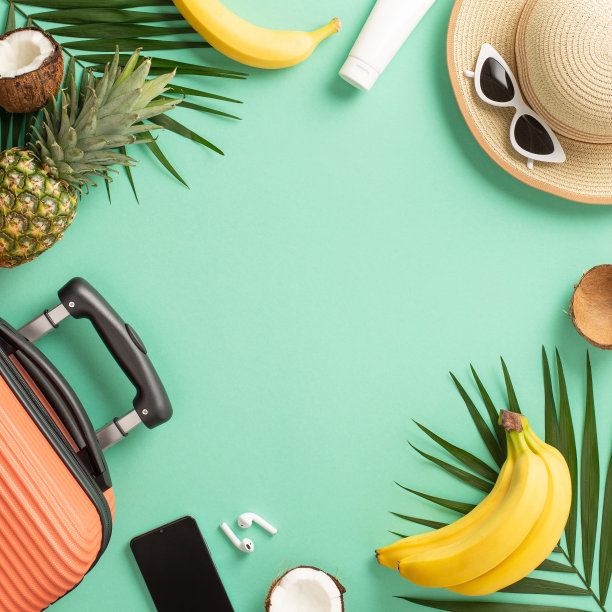热带度假概念。顶部的方形视图照片，一个手提箱和草帽，太阳镜，棕榈叶和异国情调的水果，智能手机和耳机在孤立的蓝绿色背景与copyspace图片下载