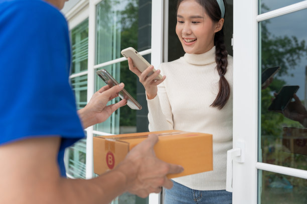 快乐的微笑亚洲女人扫描二维码支付食物。快递员送快递。网店、纸盒、外卖、邮差、快递服务、包裹、电子货币、数字转账图片下载