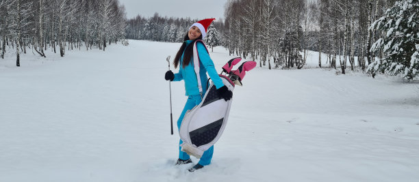 戴着圣诞老人帽子，拿着高尔夫球杆微笑的女高尔夫球手图片下载