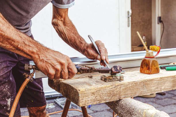 屋顶工人用铜烙铁焊接不锈钢水槽。特写手焊接锌水槽屋顶。工匠焊接到沟槽部分，将其与锡组装。图片下载