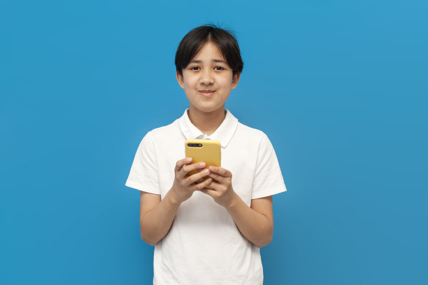 穿着白色t恤的12岁亚洲男孩在蓝色孤立的背景上使用智能手机，韩国孩子图片下载