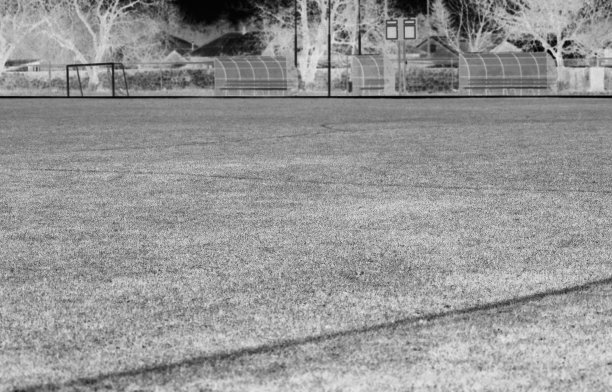 消极的，一个空旷的足球场，覆盖着草地，大门和观众看台，在冬天。黑白图片下载