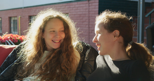 两个同龄的女学生下课后在学校大楼外模仿和戏仿。十几岁的女孩花时间在一起，建立亲密的友谊关系，拥有真实而坦诚的情感。图片下载