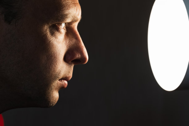 一个盯着灯光的欧洲年轻人的特写侧面肖像图片下载