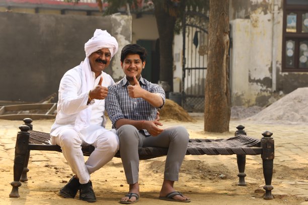 一个快乐的印度农村家庭坐在一个竖起大拇指的银行经理旁边图片下载