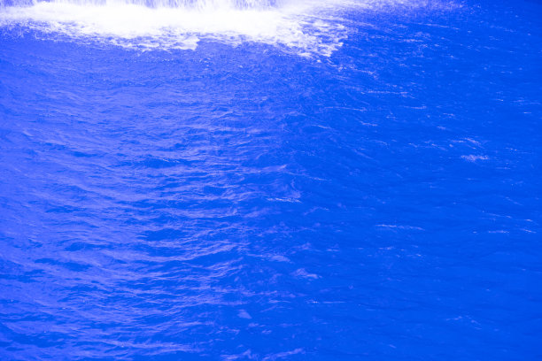 蓝蓝的水面上泛起涟漪。散焦模糊透明蓝色透明平静水面纹理与飞溅和气泡。水波与闪亮的图案纹理背景。图片下载