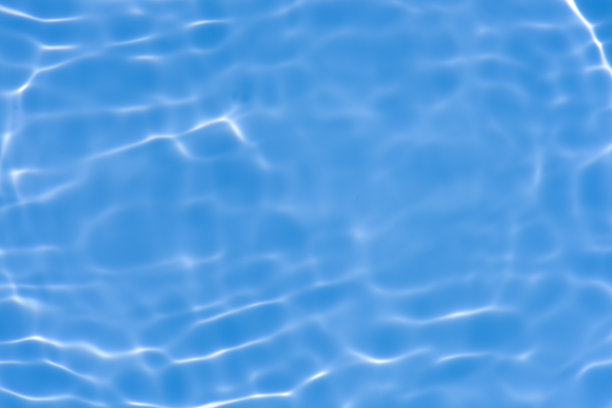 蓝蓝的水面上泛起涟漪。散焦模糊透明蓝色透明平静水面纹理与飞溅和气泡。水波与闪亮的图案纹理背景。图片下载