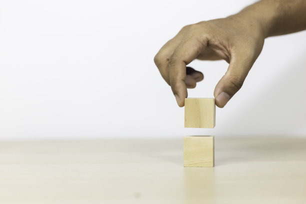 成长成功的概念。手握木块，堆叠方块，企业成长成功的阶梯。图片下载