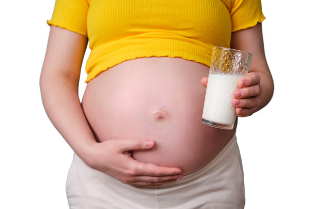 一位孕妇手中的一杯牛奶，被隔离在白色背景上图片下载