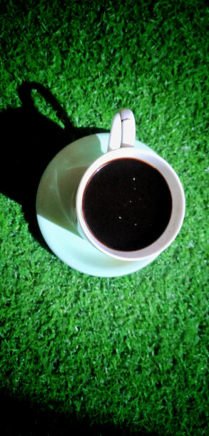 一杯没有盖子的黑咖啡，放在绿地毯上图片下载