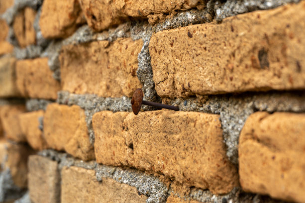 旧砖墙背景。钉子钉在红色的砖墙上。图片下载