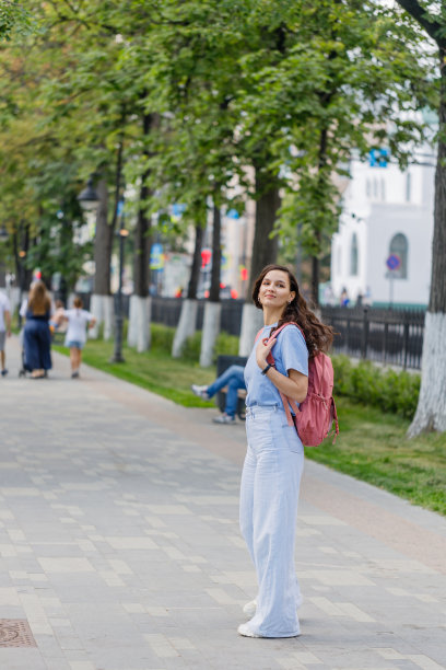 时尚积极的中年女性，穿着牛仔裤和运动鞋漫步在城市街道上图片下载