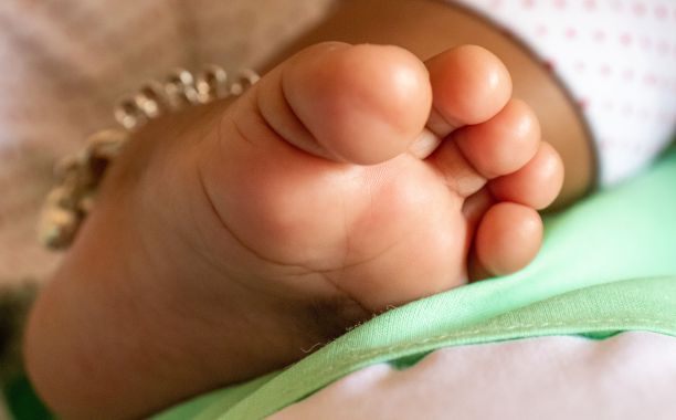 一个新生儿的脚的特写镜头，脚链放在舒适的毯子上。图片下载