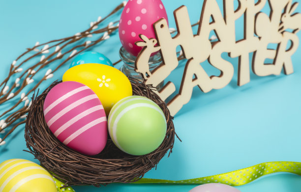 五颜六色的复活节彩蛋在巢与文字复活节快乐的蓝色背景。复活节假期概念图片下载