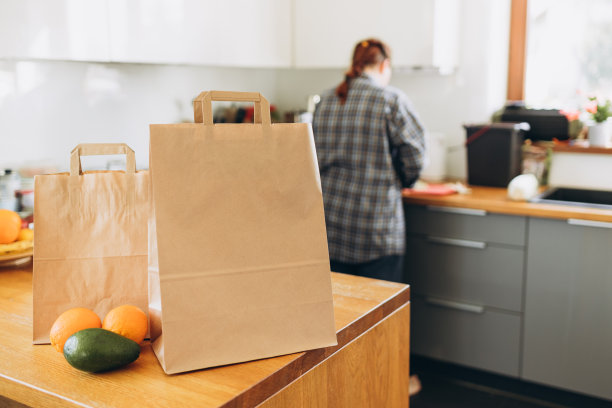 阳光明媚的日子里，木桌上的两个食品工艺袋。无论天气如何，24小时交货给客户。快餐生态包装与大早餐或晚餐设置与水果图片下载