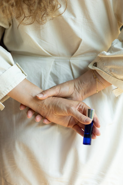 一个调香师的女朋友手里拿着一个装有香水的滚筒，背后有一张照片。天然芳香的概念来自芳香油。图片下载