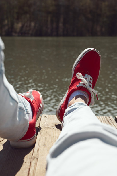 穿着红鞋的人在湖边的木甲板上放松。图片下载