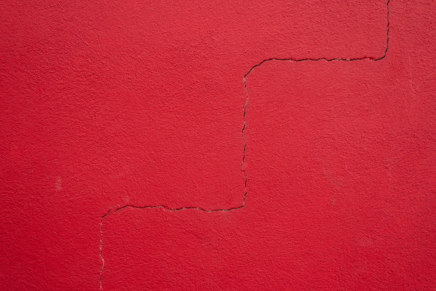 红色裂缝混凝土墙背景。粉刷抹灰砖墙背景上有一道几何裂缝。施工问题和工作质量不高图片下载