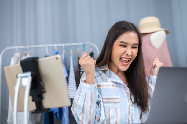 亚洲女性企业主在时装商店展示服装，在智能手机前录制视频视频直播，向顾客出售时装，网上购物概念。图片下载