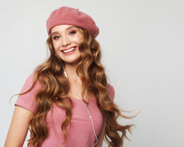 年轻快乐的女人笑着开玩笑好心情的脸孤立在灰色的背景上。女人戴着粉红色的帽子和衬衫。图片下载