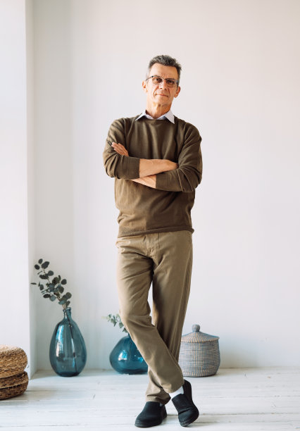 自信的人。一个开朗的休闲老人的肖像，双臂交叉站在家里，双手交叉。图片下载