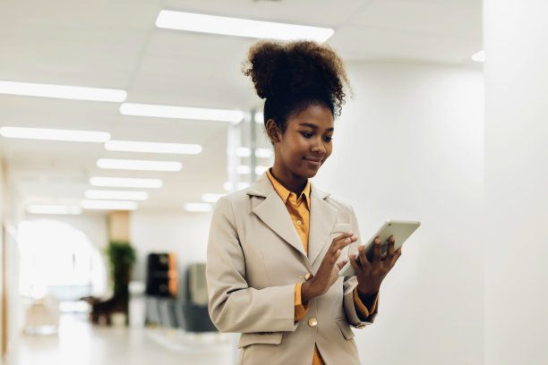 一个女人拿着一个笔记本电脑和一支笔。在现代办公室里站起来。女性领导新公司充满自信。专业自信的商务专家。图片下载