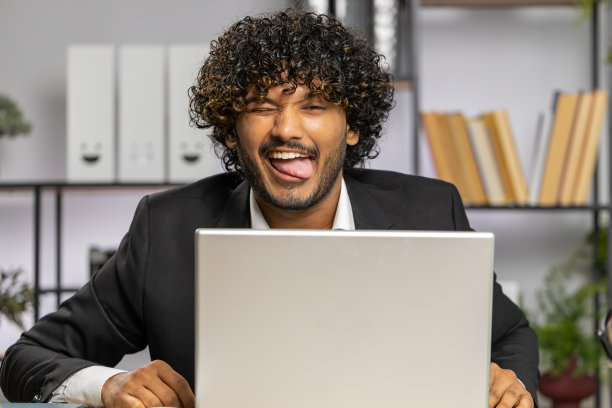 办公室里的商人躲在笔记本电脑后面做着滑稽的鬼脸鬼混，不尊重图片下载