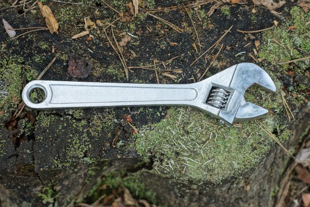 一把灰色的大扳手放在一个黑色的木桩上图片下载