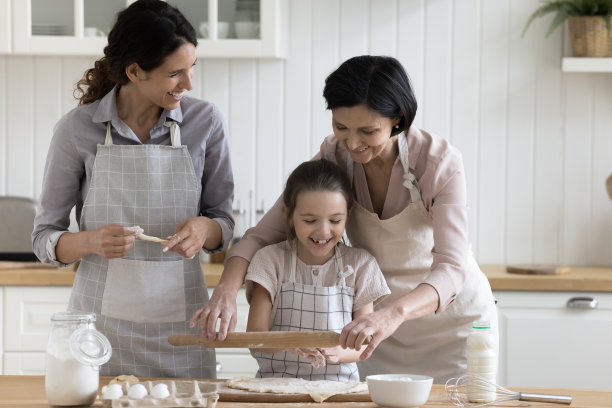 积极的女孩在家帮奶奶和妈妈烤面包图片下载