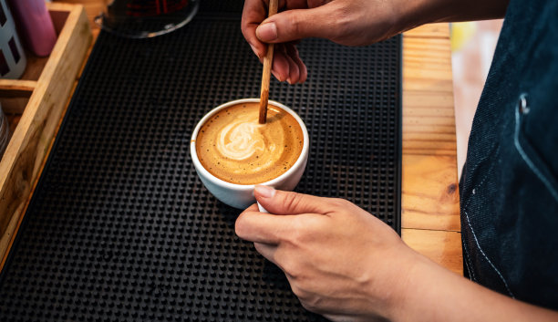 咖啡师用木勺制作或准备咖啡泡沫的特写镜头。咖啡师在煮咖啡图片下载