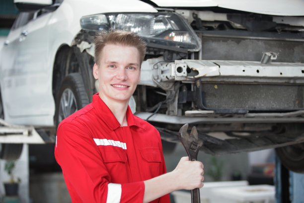 汽车修理工在汽车修理厂工作。维修服务。穿着制服的工人机械师正在用吊装车进行汽车维修。汽车维修保养。图片下载